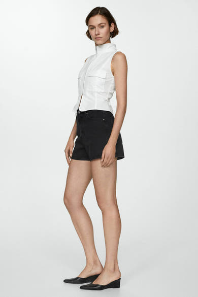 Korte noir van MANGO, gedragen met een witte mouwloze top en zwarte sleehakken.