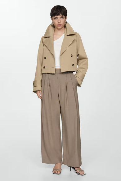 Blouse blanche sans manches de MANGO, portée avec une veste courte beige et un pantalon ample marron.