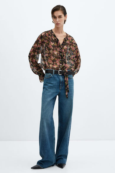 Chemisier noir à fleurs à manches longues de MANGO, avec ceinture noire et jeans bleu.