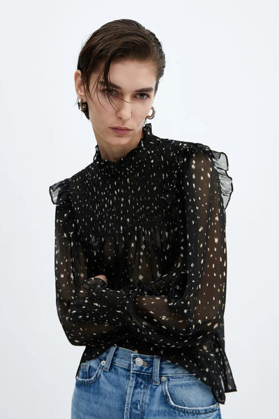 Blouse noire à manches longues de MANGO, à pois blancs et détails volantés.