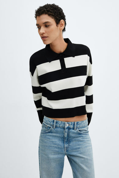 Pull noir à rayures blanches by MANGO, porté avec un jean bleu clair.