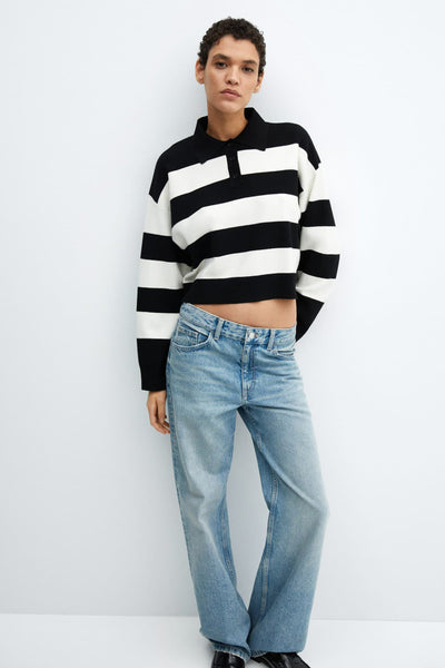 Pull noir à rayures blanches et manches longues de MANGO porté avec un jean décontracté.