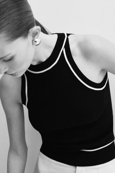 Black ribbed tank top with white trim by MANGO, side view showing round neckline and fitted silhouette on model.