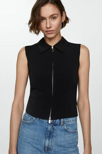 Short en denim MANGO, porté avec un haut noir zippé et des accessoires minimalistes.
