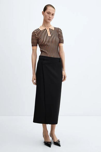 Polo brun rayé de MANGO, porté avec une jupe noire croisée et des escarpins noirs à brides.