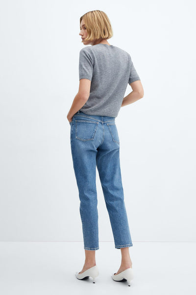 Mid blue denim mom jeans from Newmom, back view showing relaxed fit, cropped hem, and classic back pockets, worn with gray tee and white heels.