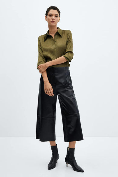 Groen overhemd met lange mouwen van MANGO, met toon-op-toon textuur, gedragen met een wijde broek van imitatieleer en zwarte enkellaarsjes.