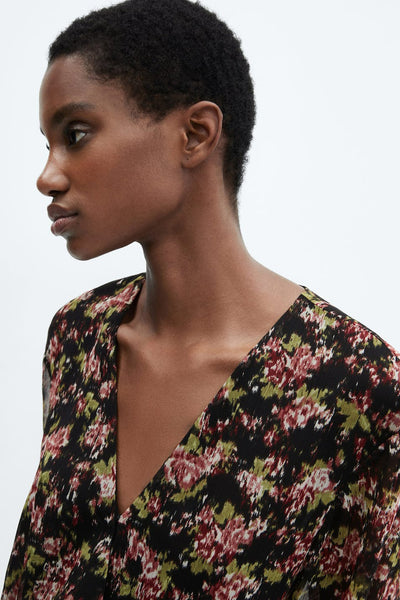 Robe midi noire de MANGO, à imprimé floral rouge et vert, avec encolure en V.
