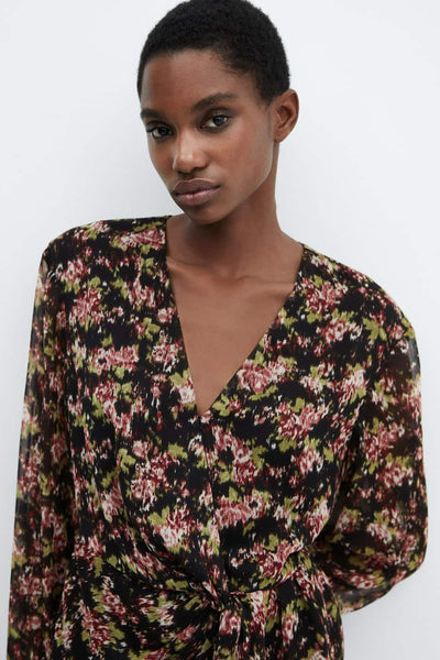 Robe midi noire de MANGO, à motif floral vert et rouge, avec un détail noué à la taille.
