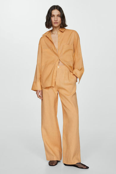 Chemise orange à manches longues, de MANGO, avec des poches plaquées et portée avec un pantalon assorti.