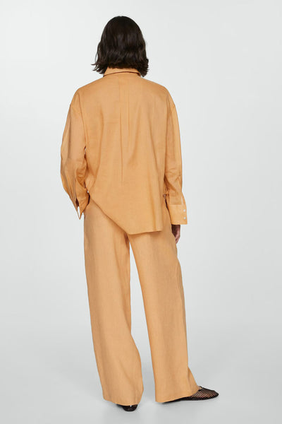 Chemisier orange à manches longues de MANGO, porté avec un pantalon assorti, vue de dos.
