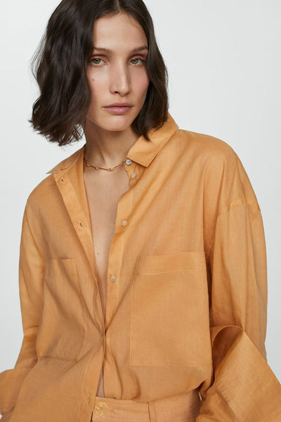 Oranje overhemd met lange mouwen van MANGO, van getextureerd linnen, gedragen open met een gouden ketting.