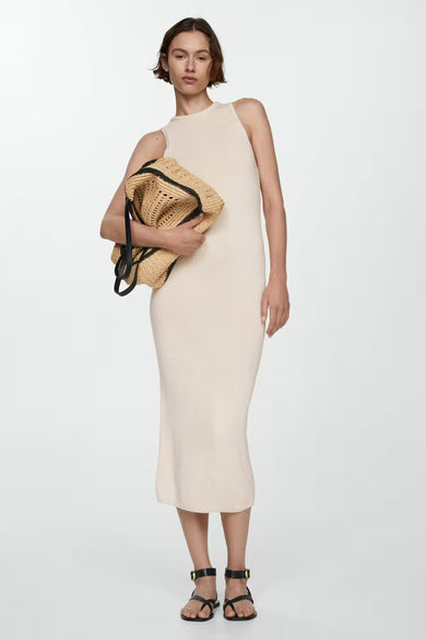Robe courte écru de MANGO, coupe ajustée longueur midi, portée avec un sac tressé et des sandales noires.
