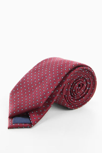 Cravate rouge à pois par MANGO, enroulée sur elle-même, détail de la doublure bleu marine.
