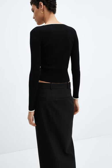Pull noir à col rond de MANGO, en maille côtelée avec bordure contrastante, porté avec une jupe noire.