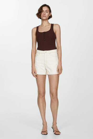 Korte beige short van MANGO met contrasterende stiksels en omgeslagen zomen, gedragen met een bruin geribd topje.