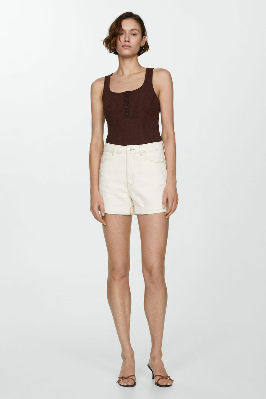 Korte beige short van MANGO met contrasterende stiksels en omgeslagen zomen, gedragen met een bruin geribd topje.