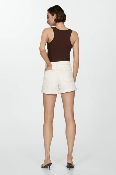 Short beige de MANGO, porté avec un débardeur marron et des mules à talons aiguilles.