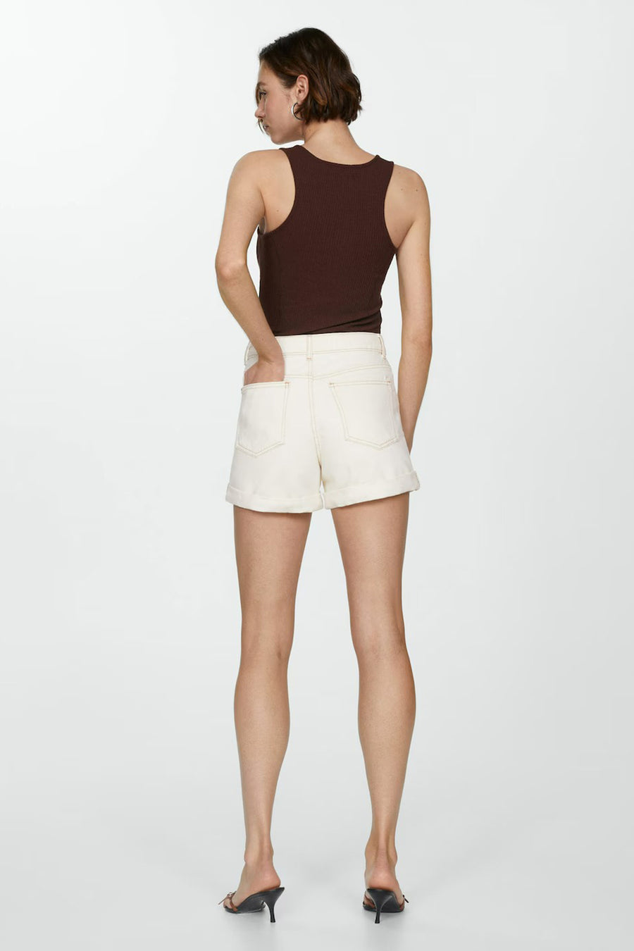 Short beige de MANGO, porté avec un débardeur marron et des mules à talons aiguilles.