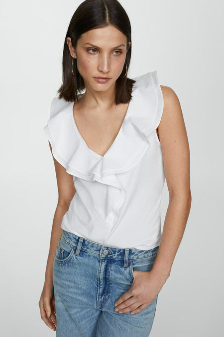 White sleeveless top with ruffled V-neckline, worn with blue jeans, front view