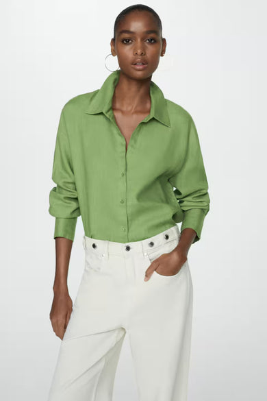 Chemisier vert à manches longues de MANGO, porté avec un pantalon blanc taille haute et des boucles d'oreilles.