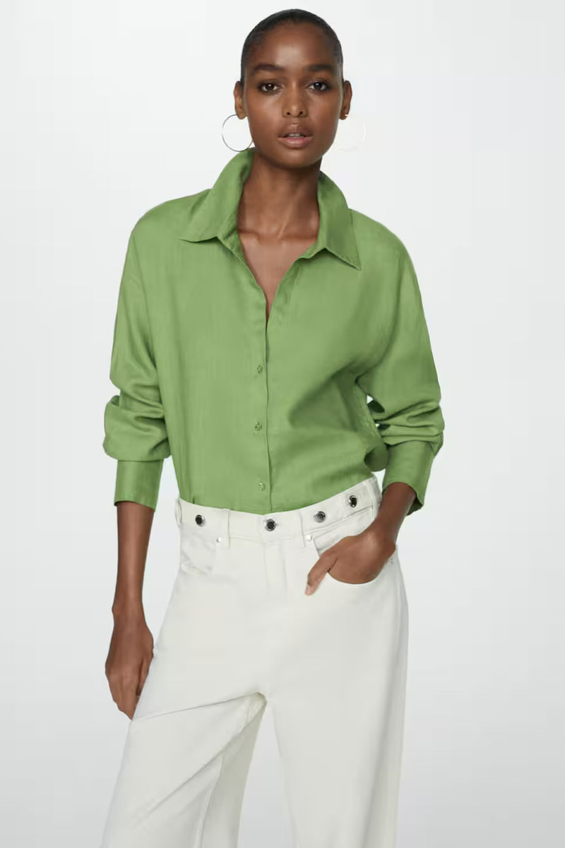 Chemisier vert à manches longues de MANGO, porté avec un pantalon blanc taille haute et des boucles d'oreilles.