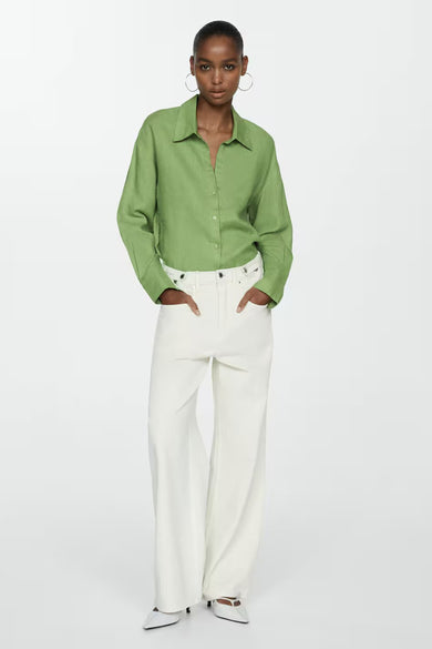 Chemisier à manches longues vert de MANGO, porté avec un pantalon blanc taille haute et des escarpins.