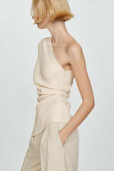 Blouse beige asymétrique de MANGO, avec un design drapé élégant et une fermeture éclair discrète sur le côté.