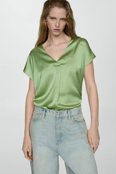 T-shirt vert à manches courtes de MANGO, porté avec un jean taille haute délavé.
