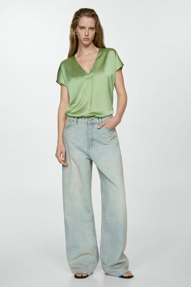 T-shirt vert à manches courtes de MANGO, porté avec un jean bleu clair ample et des sandales noires.
