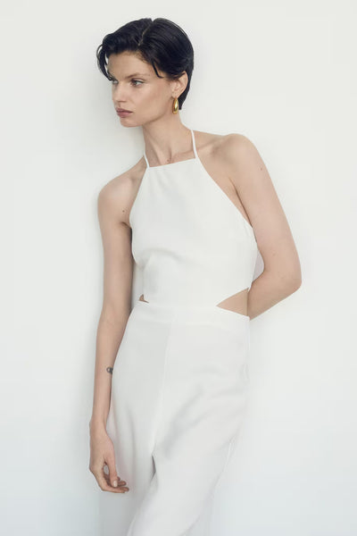 Combinaison beige Mango avec découpe à la taille, portée avec des boucles d'oreilles dorées.