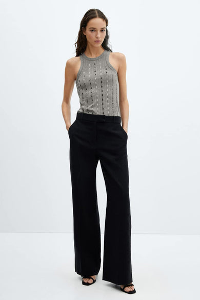Débardeur gris de MANGO, à côtes avec détails ajourés, porté avec un pantalon noir à jambes larges et des sandales.
