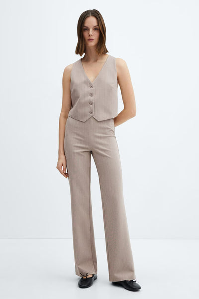 Tailleur veste-pantalon rayé brun de MANGO, porté avec des chaussures plates noires.