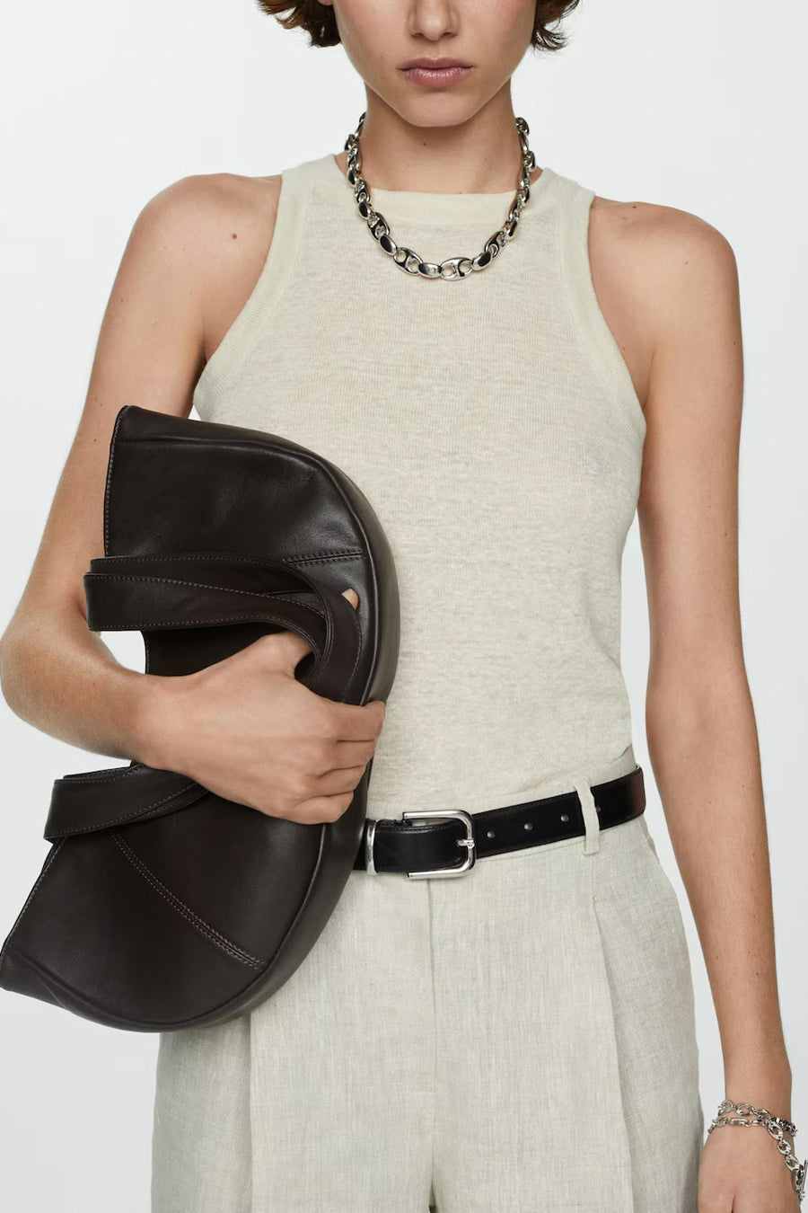 Beige tanktop van MANGO, gedragen met een lichte broek en een zilveren ketting met grote schakels.