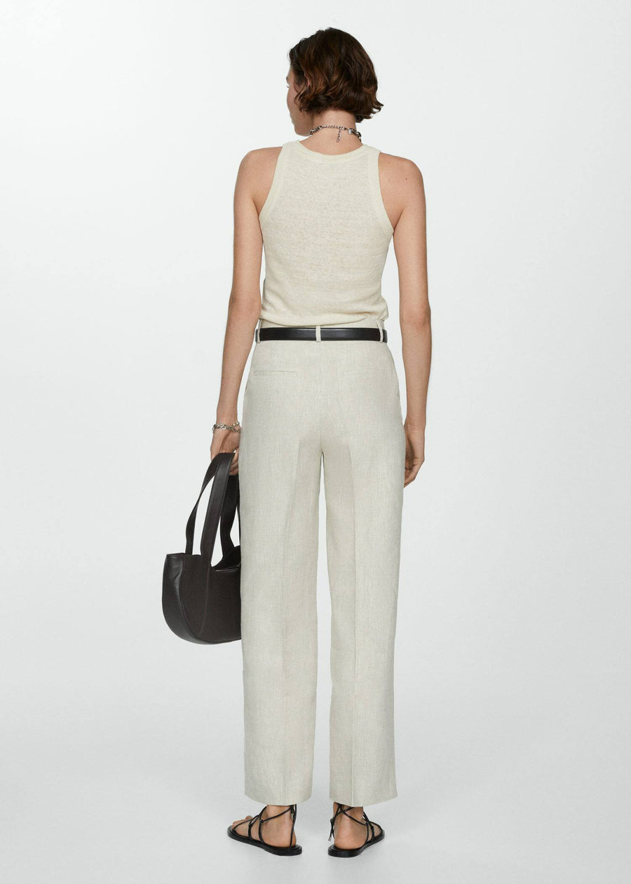 Beige tanktop van MANGO, gedragen met een broek met hoge taille, zwarte riem en sandalen met bandjes.