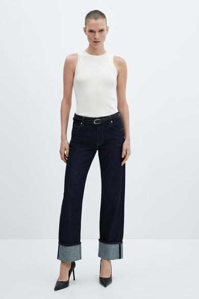 Top écru sans manches de MANGO, porté avec un jean taille haute et des talons noirs.
