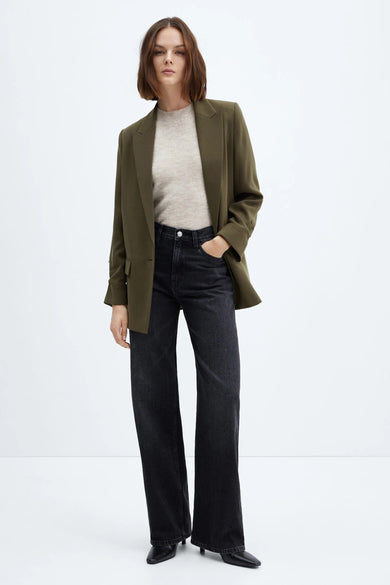 Blazer vert signé MANGO, porté avec un pull beige et un jean noir taille haute à jambes larges.