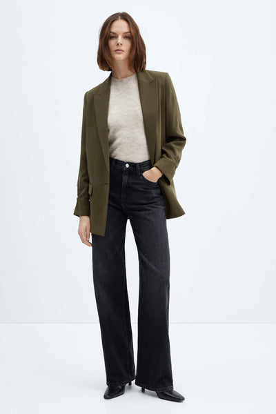 Blazer vert signé MANGO, porté avec un pull beige et un jean noir taille haute à jambes larges.