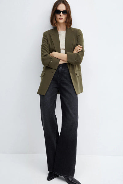 Blazer vert de MANGO, porté avec un t-shirt crème, un jean taille haute noir et des bottines pointues.