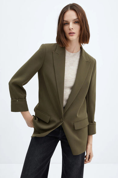 Blazer vert de MANGO, avec revers, poches à rabat, porté avec un pull clair et un jean noir
