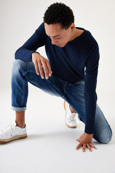 Jean slim en denim bleu moyen de GARCIA, porté avec un t-shirt bleu marine et des chaussures de sport blanches.
