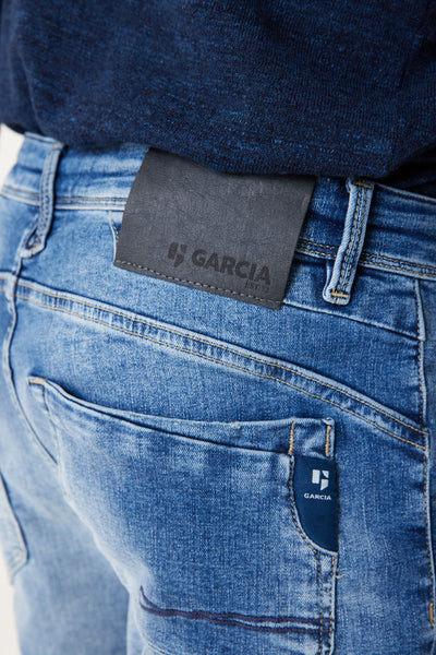 Jean slim bleu moyen de GARCIA, avec étiquette en cuir logotée et couture contrastée sur la poche.