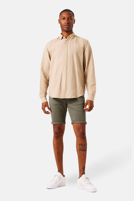 Short en jean kaki de GARCIA, porté avec une chemise beige et des chaussures blanches.