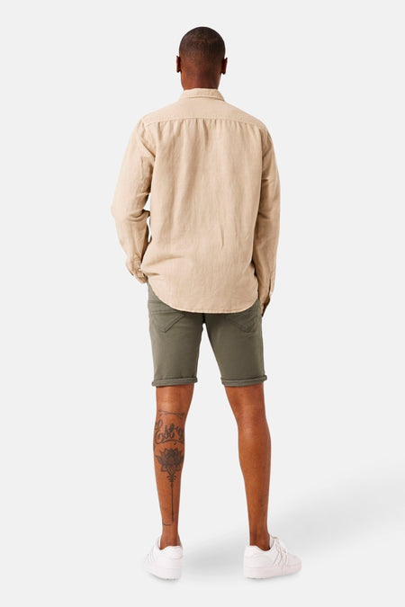 Short en jeans kaki de GARCIA, avec ourlet roulé, porté avec une chemise beige et des chaussures de sport blanches.