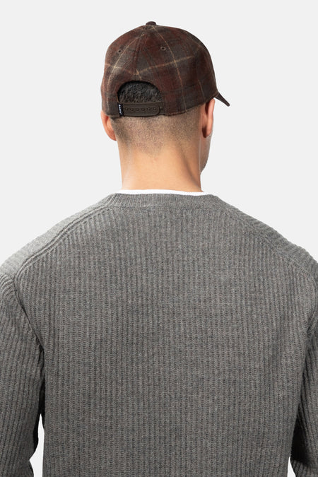 Vue arrière d’une casquette brune à carreaux BARTS portée par un modèle.