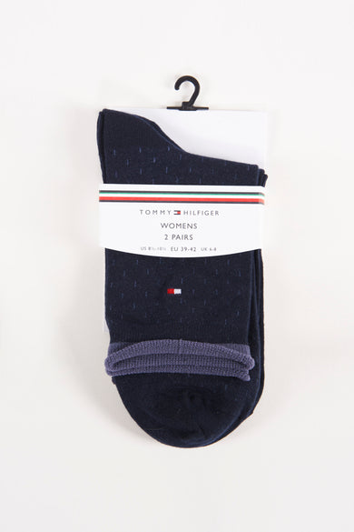 Navy blue women's socks with subtle speckled texture by Tommy Hilfiger, featuring red-white-blue flag logo and ribbed heel, packaged on hanger.