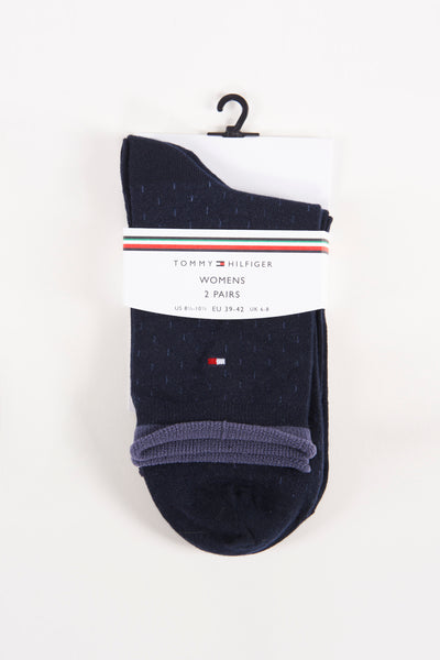 Navy blue women's socks with subtle speckled texture by Tommy Hilfiger, featuring red-white-blue flag logo and ribbed heel, packaged on hanger.