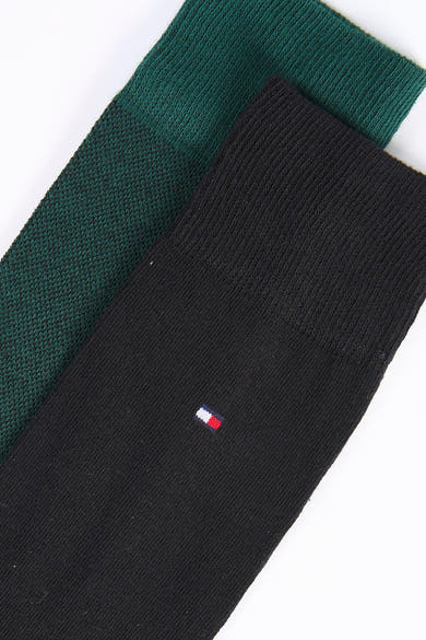 Gros plan sur des chaussettes courtes TOMMY JEANS noires et vert foncé, avec un petit drapeau tricolore brodé.