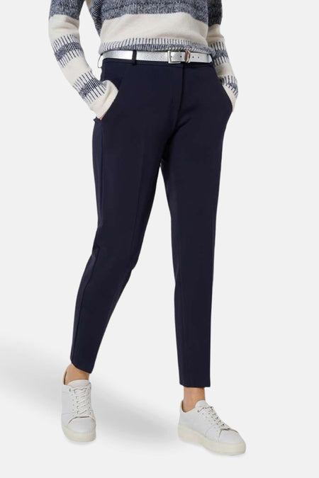 Blauwe pantalon van BRAX, met zilveren riem en discrete achterzakken, gedragen met witte sneakers.