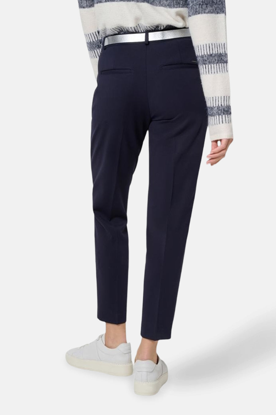Pantalon de costume bleu de BRAX, avec ceinture argentée et poches arrière discrètes, porté avec des baskets blanches.
